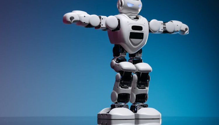 A white humanoid toy robot with raised arms on a glass table, against a blue gradient backdrop.